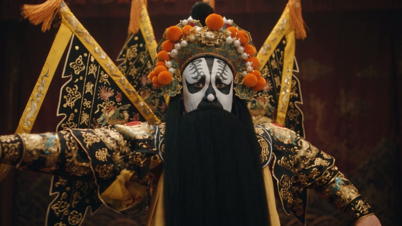Ein Darsteller der Peking-Oper mit bemalter Maske und goldbesticktem Kostüm auf einer dunklen Bühne.