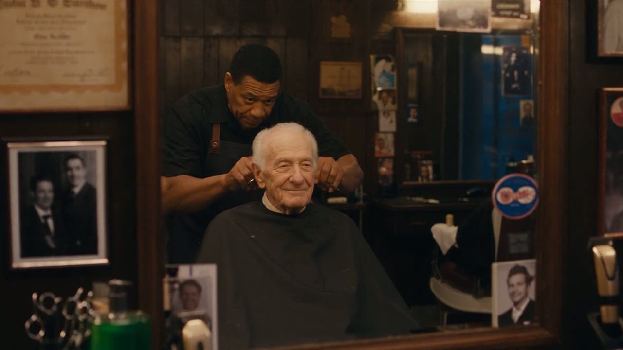 Een oude kapper knipt de bakkebaarden van een klant in een kleine kapperszaak in de schemering.